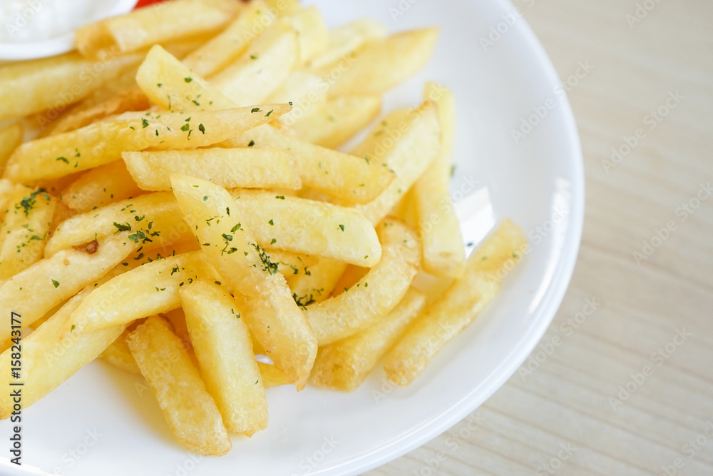 Fresh french fries fried potato sticks parsley topped with ketchup and mayonnaise on white plate Fresh french fries fried potato sticks parsley topped with ketchup and mayonnaise on white plate