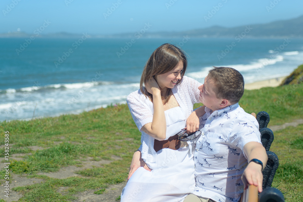 Young romantic couple hugging on the bench at seaside