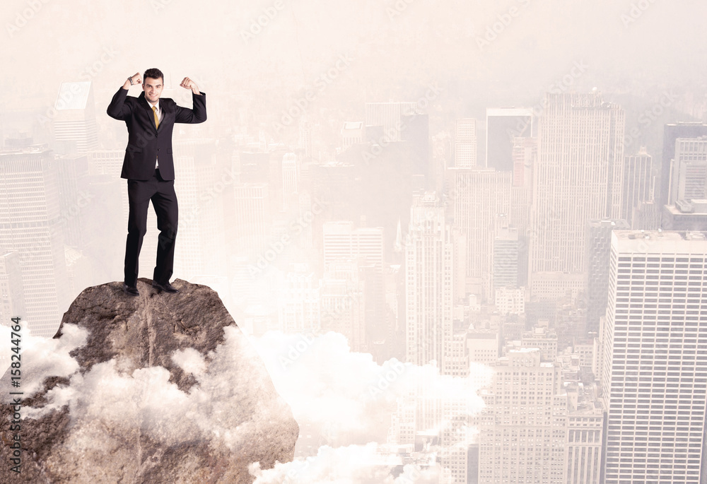 Happy businessman standing on stone top Happy businessman standing on stone top