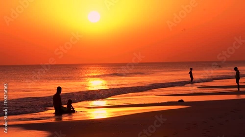 Ojciec z dzieckiem na plaży przy zachodzie słońca