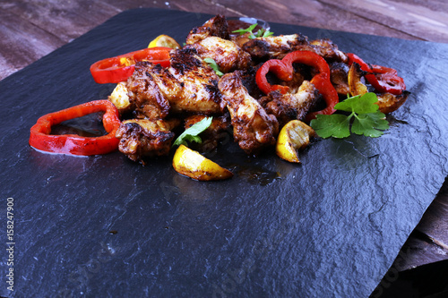 barbecue chicken wings close up on stone tray with pepper and lime