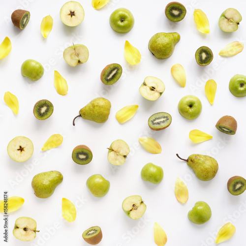 Fruits on a white background. Pattern of vegetables and fruits. Food background. Collage of food. Top view. Composition from pears, green apples, kiwi and yellow petals of a tulip.