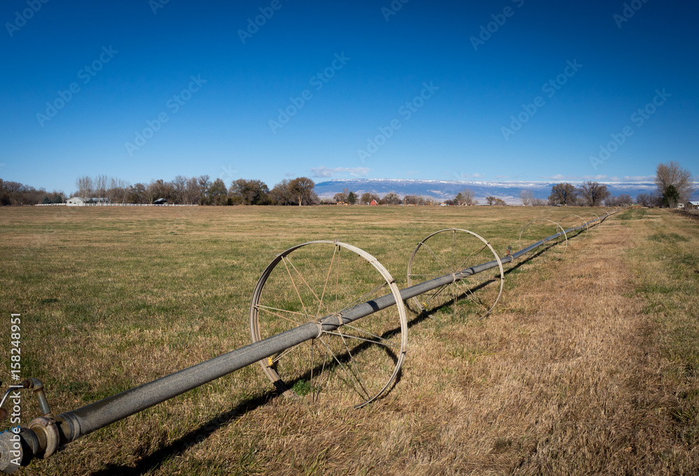 Wheeled irrigation in field in western colorado with farms and snow capped mountains
