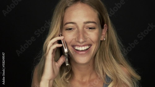 Young woman receiving good news and laughing while talking on cell phone photo