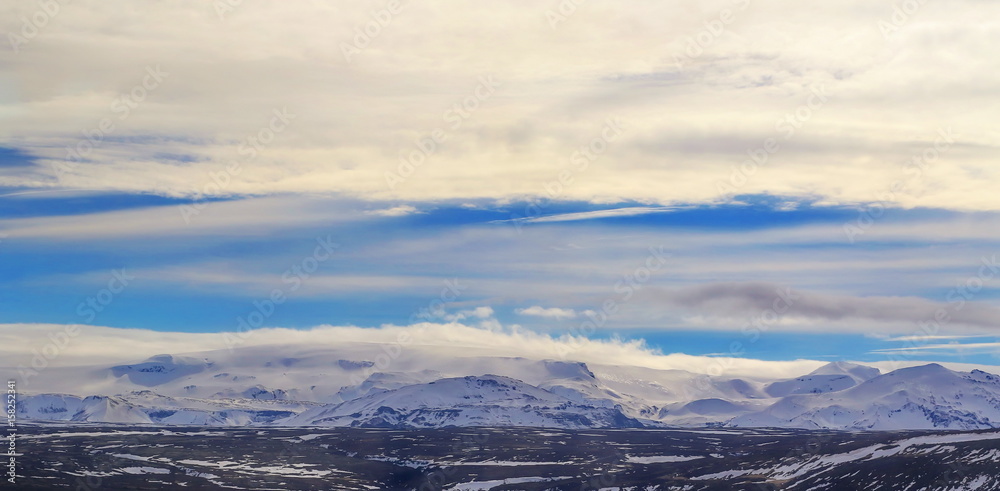 Icelandic landscape with mountains and snow in the distance