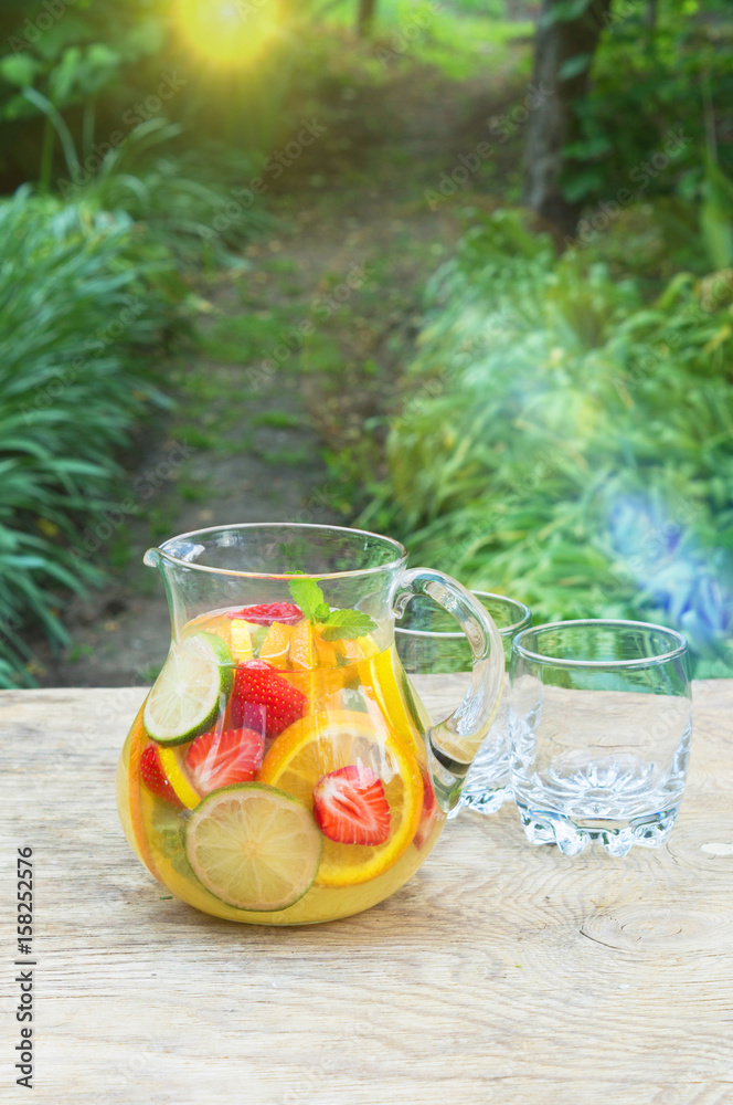 Refreshing fruit water in the decanter outdoors in the garden. Refreshing fruit water in the decanter outdoors in the garden.