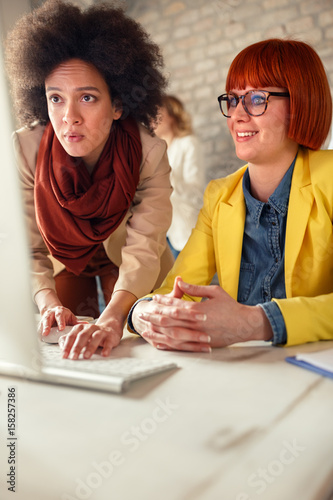 Afro-American girl adjusts computer to co-worker colleague