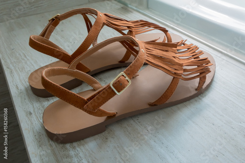Fototapeta Naklejka Na Ścianę i Meble -  A pair of modern brown leather sandals on marble background