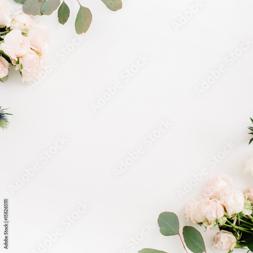 Border frame made of beige rose flowers, eringium flower, eucalyptus branches on white background. Flat lay, top view. Floral background
