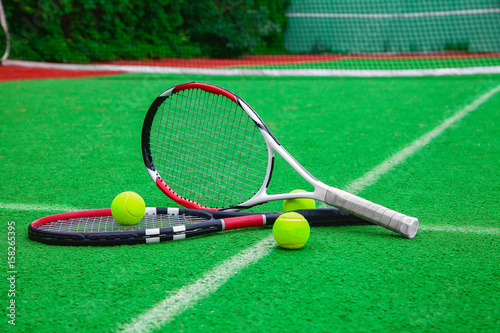 tennis racket with balls on green background © borisblik