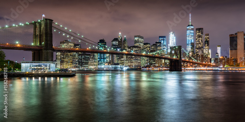 Panoramic view of the Brooklyn Bridge with Financial District skyscrapers at twilight and light clouds. Lower Manhattan, New York City