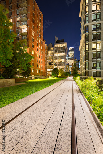 Photography Highline promenade and old railway tracks at twilight with high-rises and building lights in Chelsea