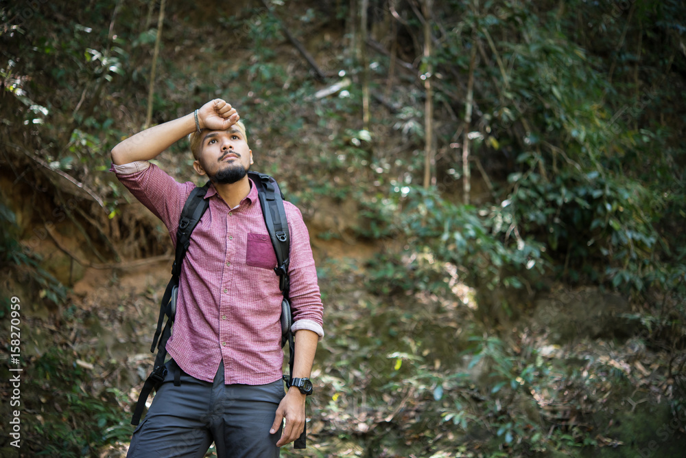 Young attractive man sitting in the forest and resting during hiking. Young attractive man sitting in the forest and resting during hiking.