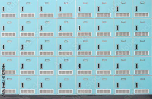 A front on view of a stack of Spring green metal school lockers with combination locks and doors shut as background
