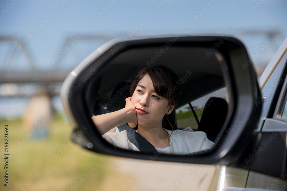 young female driver is reflected in a car side mirror.