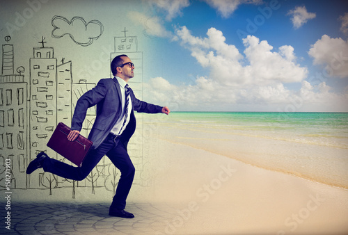 Quadro su tela Businessman running away from a life in a city to the sunny beach