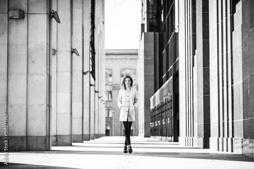 Front view. Young fashionable woman. In the background concrete wall.