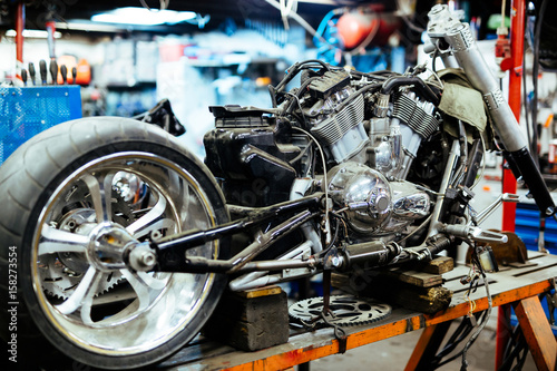 Background image of big disassembled motorcycle on stand in workshop, ready for repair, tune up and customizing works