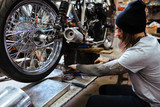 Portrait of tattooed biker working in garage repairing broken motorcycle and customizing it