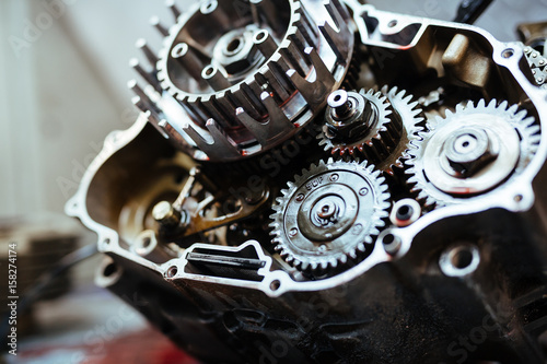 Closeup image of metal car part with gears smudged with machine oil on table in mechanics workshop
