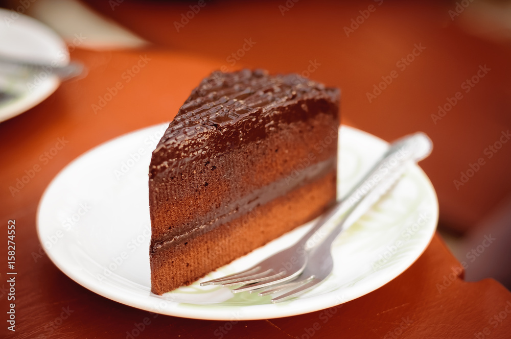 Pieces of delicious chocolate cake with fork on dish in coffee shop Pieces of delicious chocolate cake with fork on dish in coffee shop
