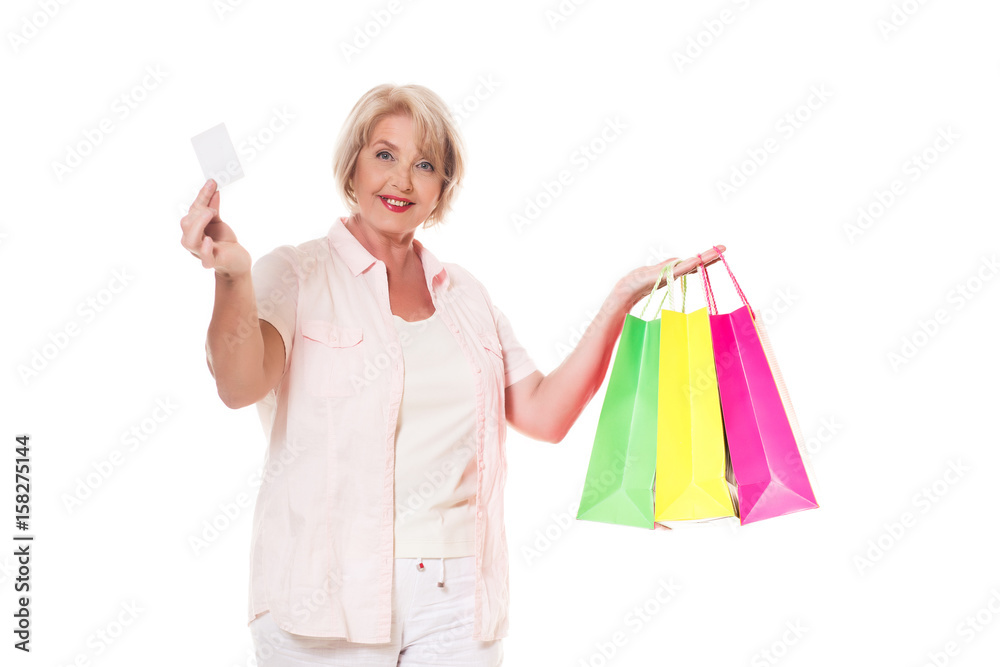 Elderly woman on a white background with shopping bags and a bank card Elderly woman on a white background with shopping bags and a bank card