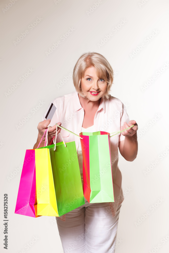 Elderly woman on a white background with shopping bags and a bank card Elderly woman on a white background with shopping bags and a bank card