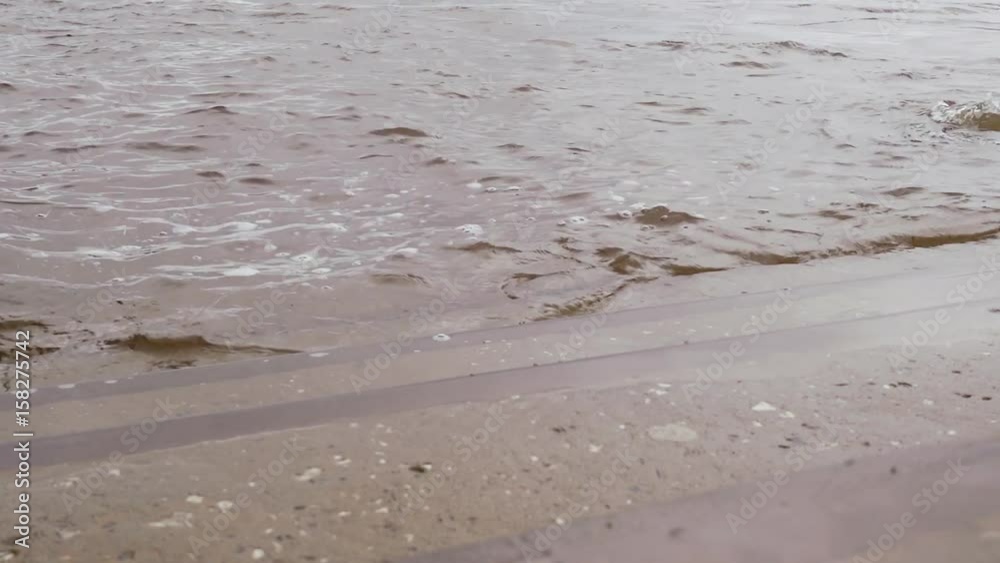 The wet steps of a ladder on the river bank with small waves The wet steps of a ladder on the river bank with small waves