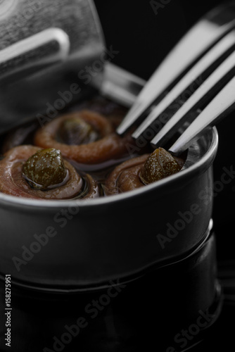 Anchovy rolls with capers in olive oil in tin. Close up