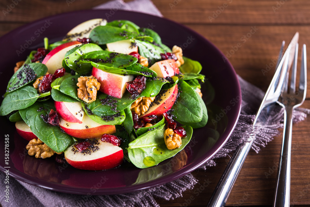 Healthy salad plate with apple, dried cranberry, walnut, spinach and poppy seed dressing on wooden background close up. Food and health. Clean eating.
