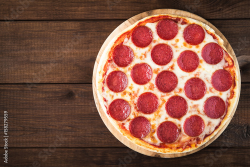 Italian Pepperoni pizza with salami on dark wooden background top view. Italian traditional food. Popular street food.