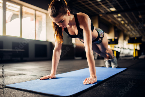 Female athlete doing push-up exercises in gym photo