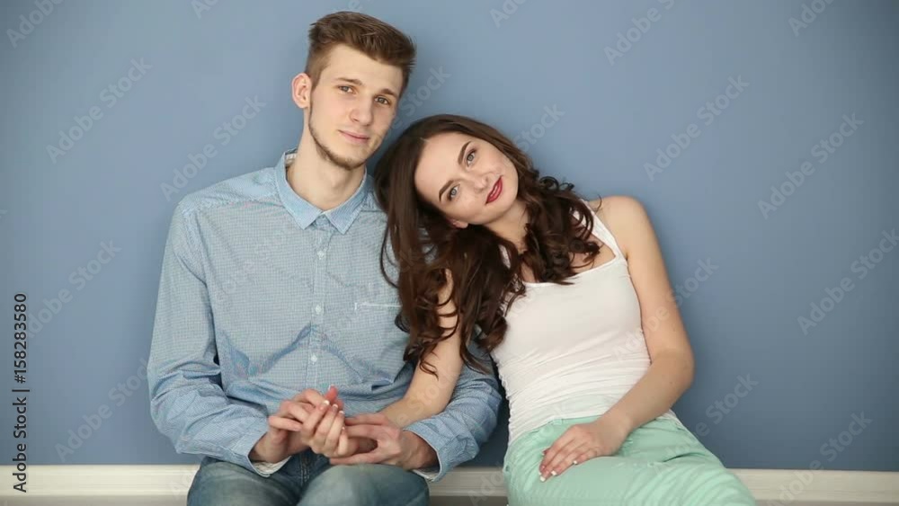 Young couple in love sitting at home by the blue wall Young couple in love sitting at home by the blue wall