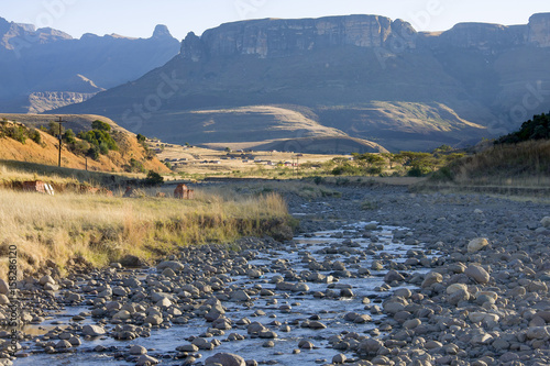 Landscape-orientated view of the Drakensberg Mountain Range in KwaZulu-Natal province of South Africa.  A stream runs in the foreground.