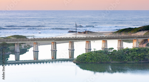 Fototapeta Naklejka Na Ścianę i Meble -  Reflection of a railway bridge crossing a lagoon on the KZN South Coast of South Africa.