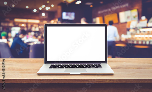 Modern computer,laptop with blank screen on table with blur cafe,restaurant backgrounds.