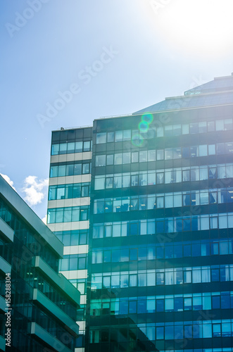 The building is a business center glass with green and blue windows, sunlight and glare