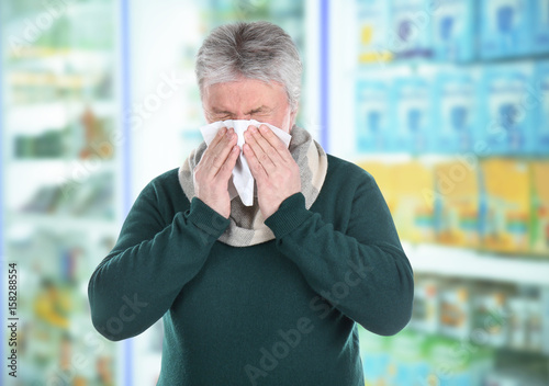 Senior man blowing nose on ...