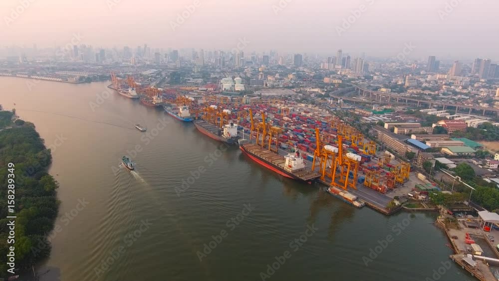 Aerial view of container ships and lifting cranes in the Port of Bangkok. Aerial view by drone; container ships at Bangkok. Aerial shot of the containers on sunset. Aerial view of container ships and lifting cranes in the Port of Bangkok. Aerial view by drone; container ships at Bangkok. Aerial shot of the containers on sunset.