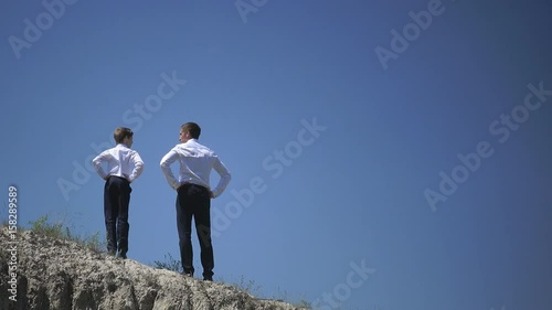 Father and son stand on top of a hill and look to the sky, free and happy, family holiday, winners