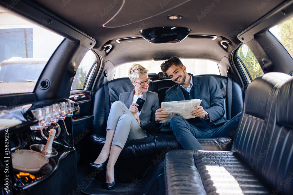 Partners in limo looking at newspaper