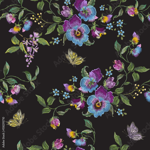 Embroidery trend floral seamless pattern with pansies and butterflies. Vector traditional embroidered flowers decor on black background for fabric design.