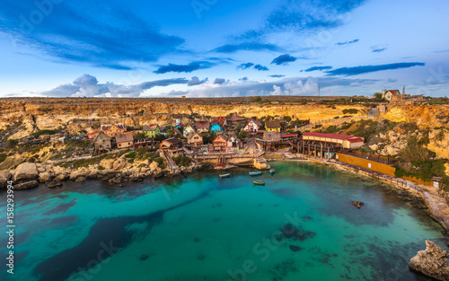 Mellieha, Malta - The famous Popeye Village at Anchor Bay at sunset with amazing colorful clouds and sky
