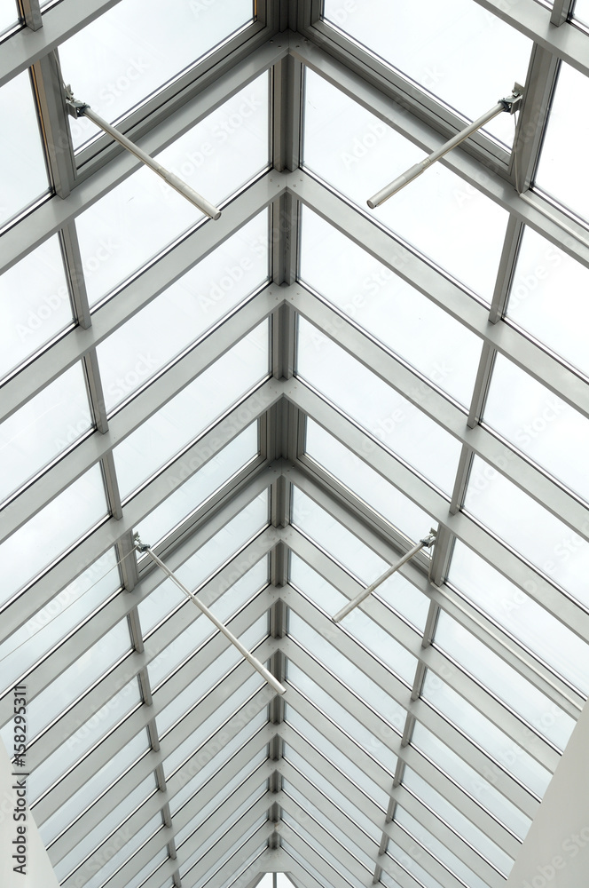 A view through a triangular arched glass roof to the overcast sky, white aluminum frames, double-glazed windows. Photo partially toned A view through a triangular arched glass roof to the overcast sky, white aluminum frames, double-glazed windows. Photo partially toned