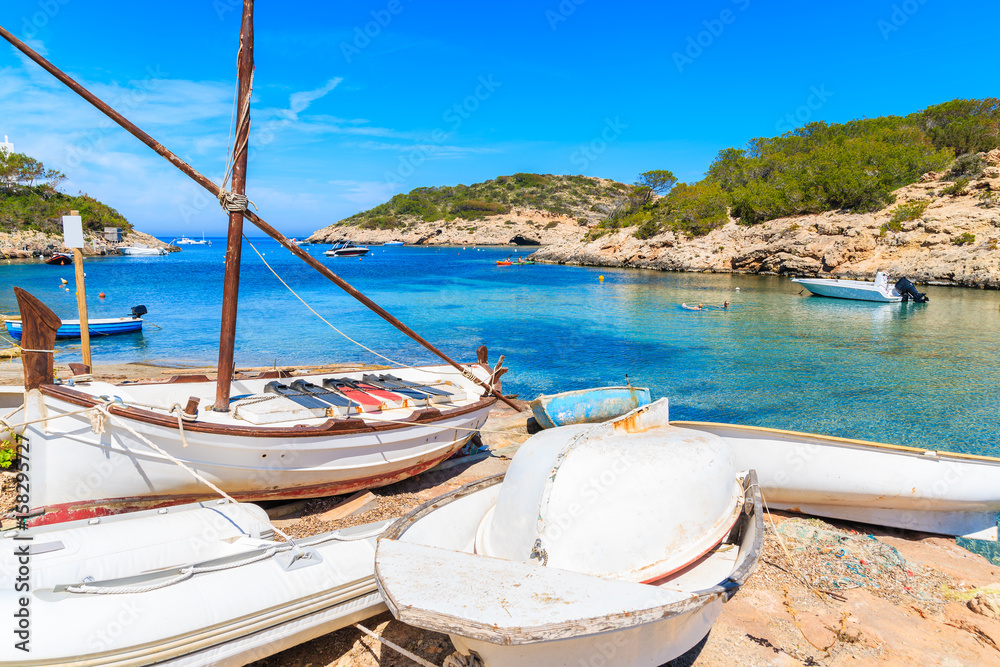 White fishing boats on shore Cala Portinatx bay, Ibiza island, Spain