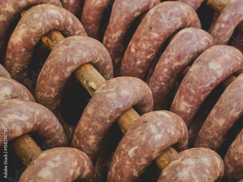 A group of smoked sausages hung on a stick over a smoke. This is a natural tasty product without preservatives or chemicals.
