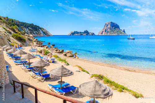 Obraz na płótnie View of Cala d'Hort beach with sunbeds and umbrellas and beautiful azure blue se