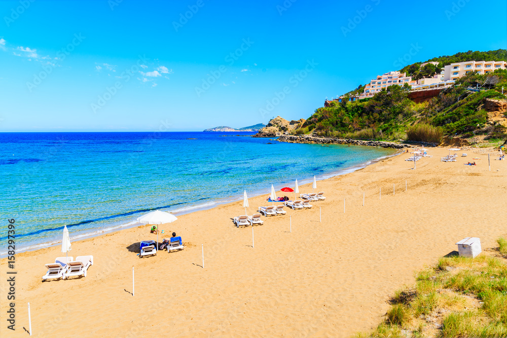 View of sandy Es Figueral beach with sunbeds and umbrellas, Ibiza island, Spain