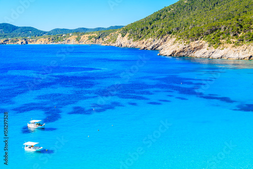 Fishing boats on blue sea water of Cala San Vicente bay, Ibiza island, Spain