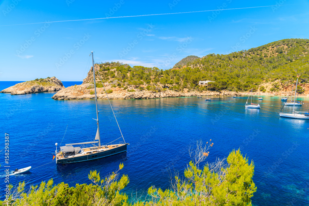 Sailing boat on blue sea water in Cala Salada bay, Ibiza island, Spain